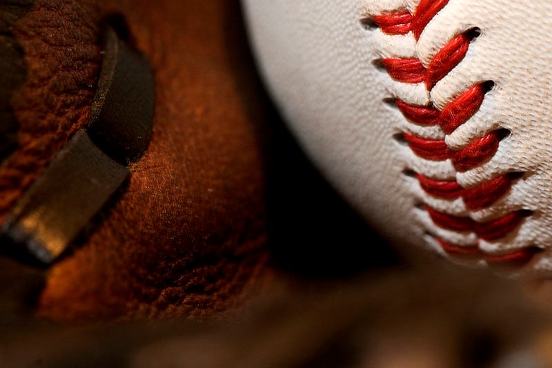 Close-up of a baseball resting in a worn leather glove