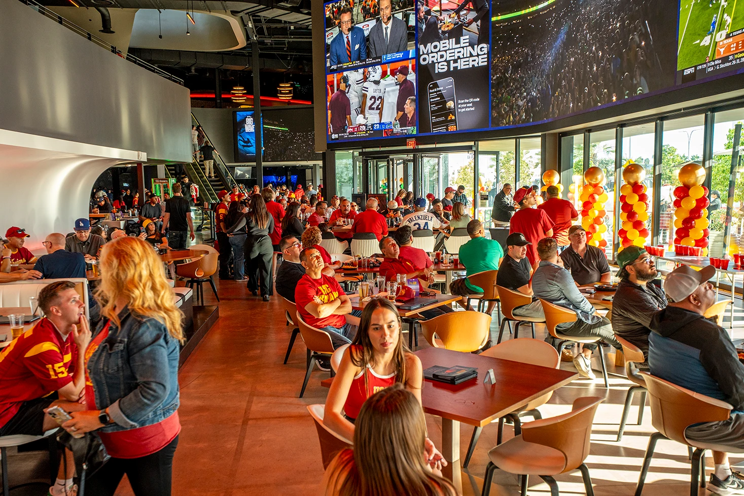 A packed game-day crowd watching wall-to-wall screens in The Hall at Cosm Los Angeles