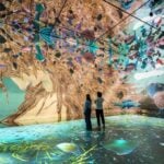 Visitors surrounded by projected artwork in the Beyond Reality gallery at Frameless