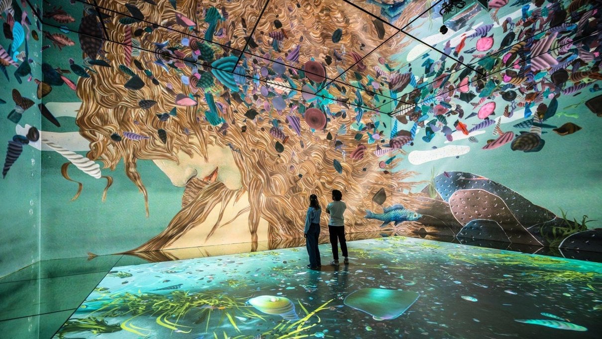 Visitors surrounded by projected artwork in the Beyond Reality gallery at Frameless
