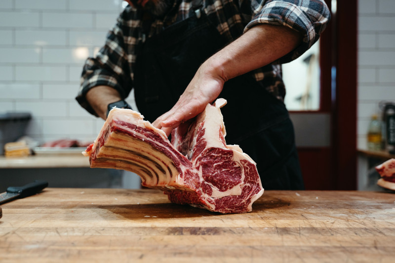 A butcher holding raw beef at a Host location