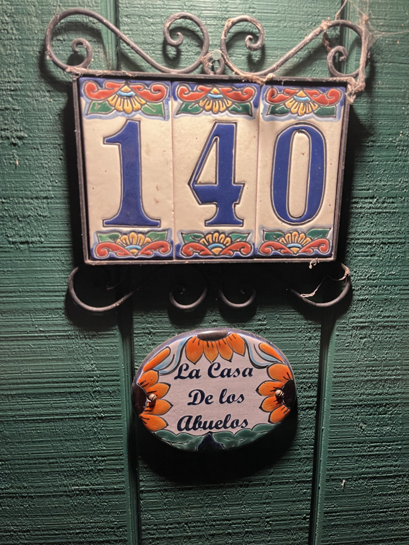 Decorative ceramic house number sign on a green wall