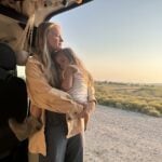 Woman and child beside an RV in the early morning