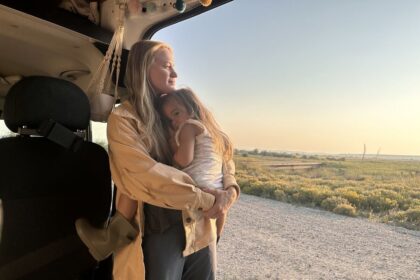 Woman and child beside an RV in the early morning