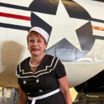 Woman standing beside a historic warbird fuselage