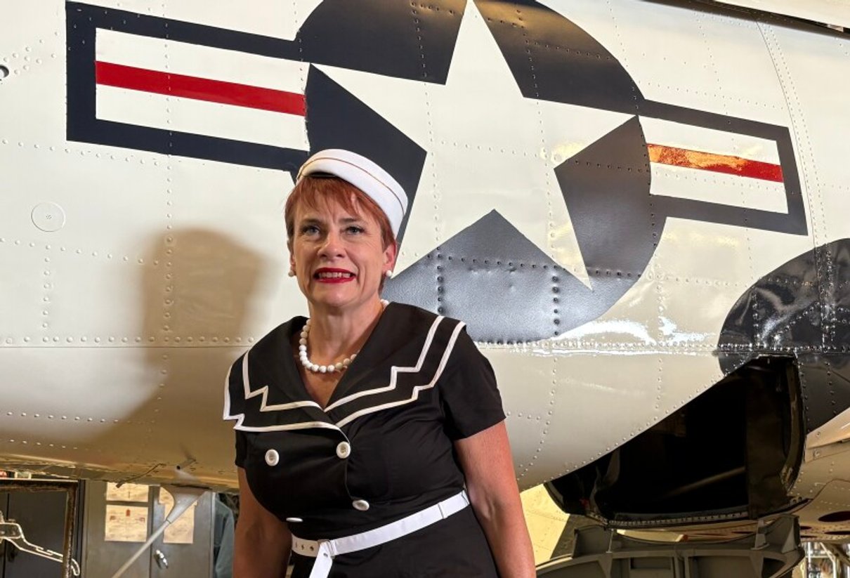 Woman standing beside a historic warbird fuselage