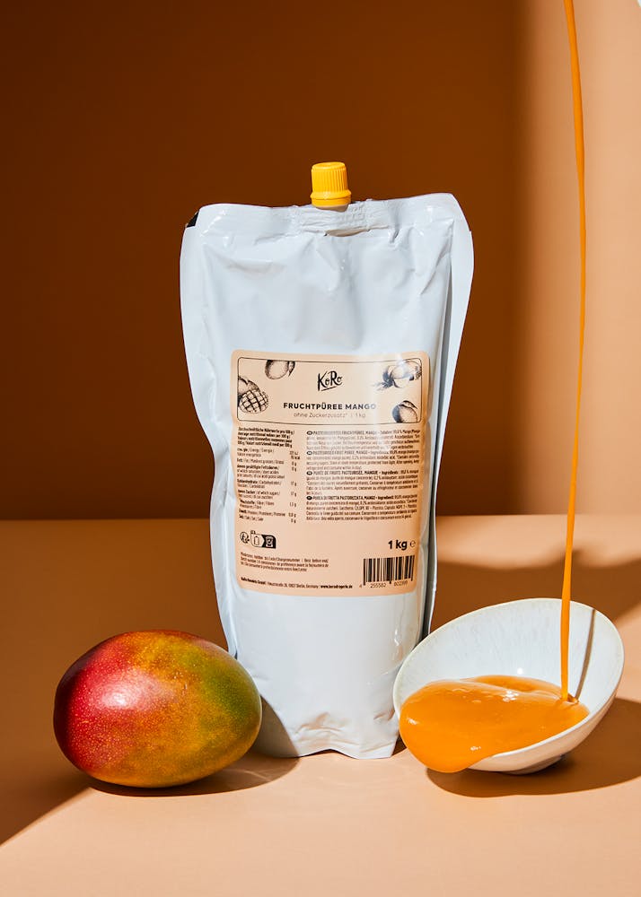 Beutel mit KoRo Fruchtpüree Mango neben einer frischen Mango