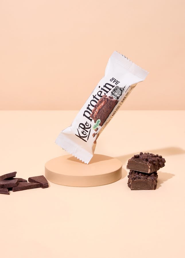 Veganer Schokoladen-Proteinriegel auf beigefarbenem Hintergrund
