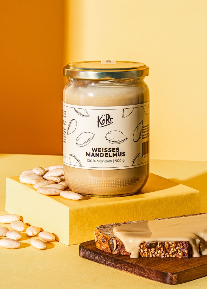 Glas mit weißem Mandelmus neben Brot auf einem Tisch