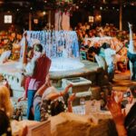 Couple dancing by the illuminated fountain as the crowd cheers at Mamma Mia! The Party
