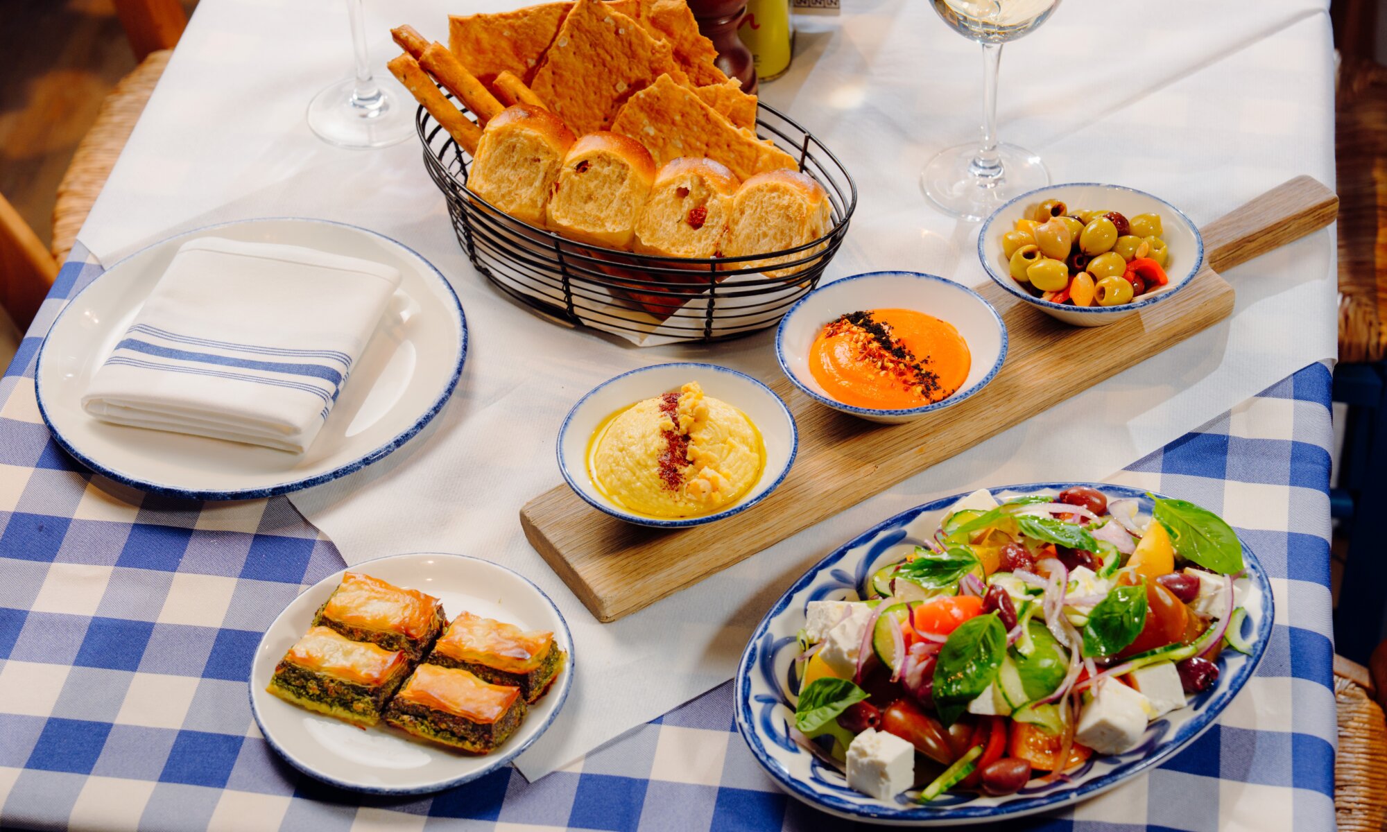 Greek mezze sharing platter with breads, dips, olives, spanakopita and Greek salad