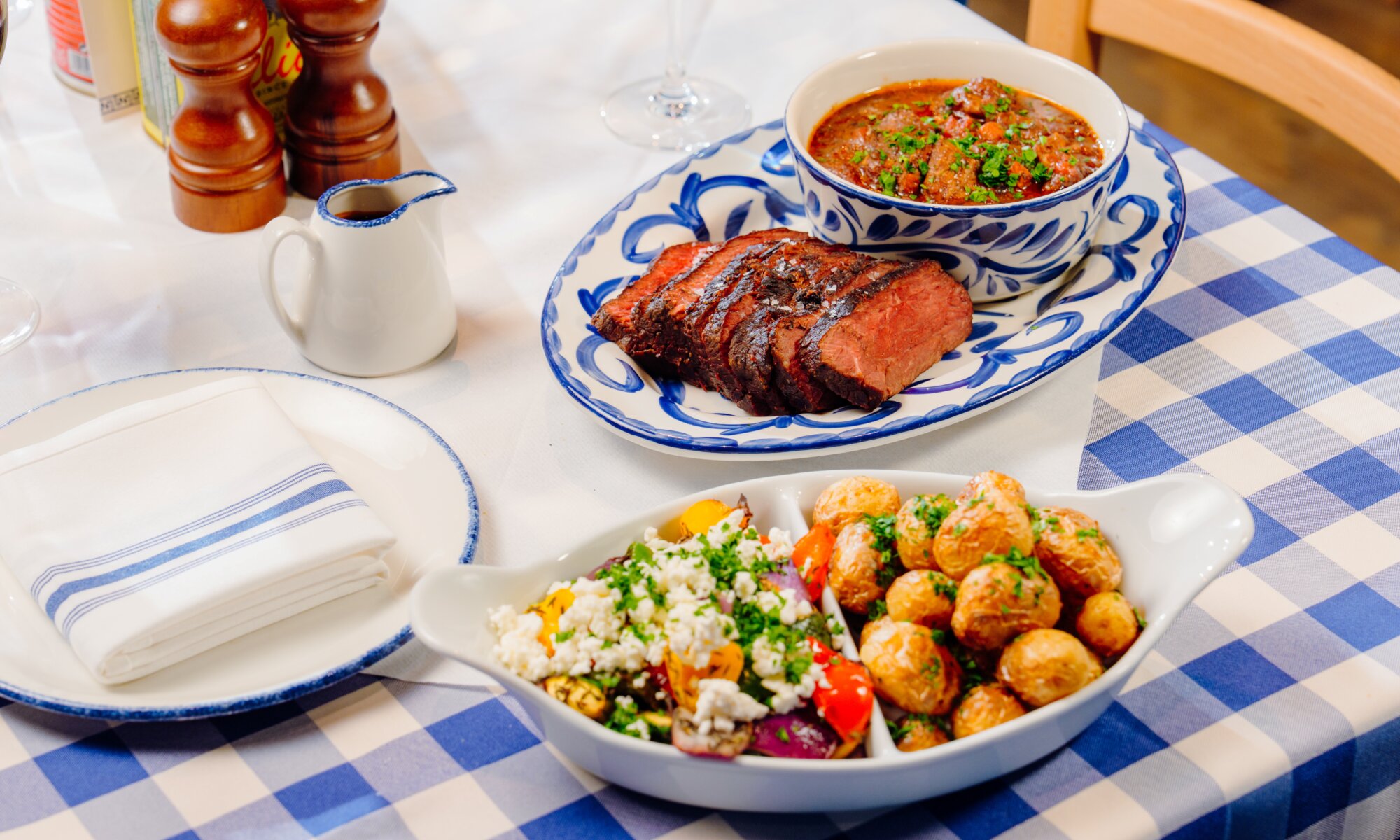 Main course of sliced beef, lamb stifado, roasted baby potatoes and vegetables