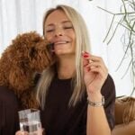 Femme assise avec un chien et un flacon KSM-66 Ashwagandha Nature’s Finest