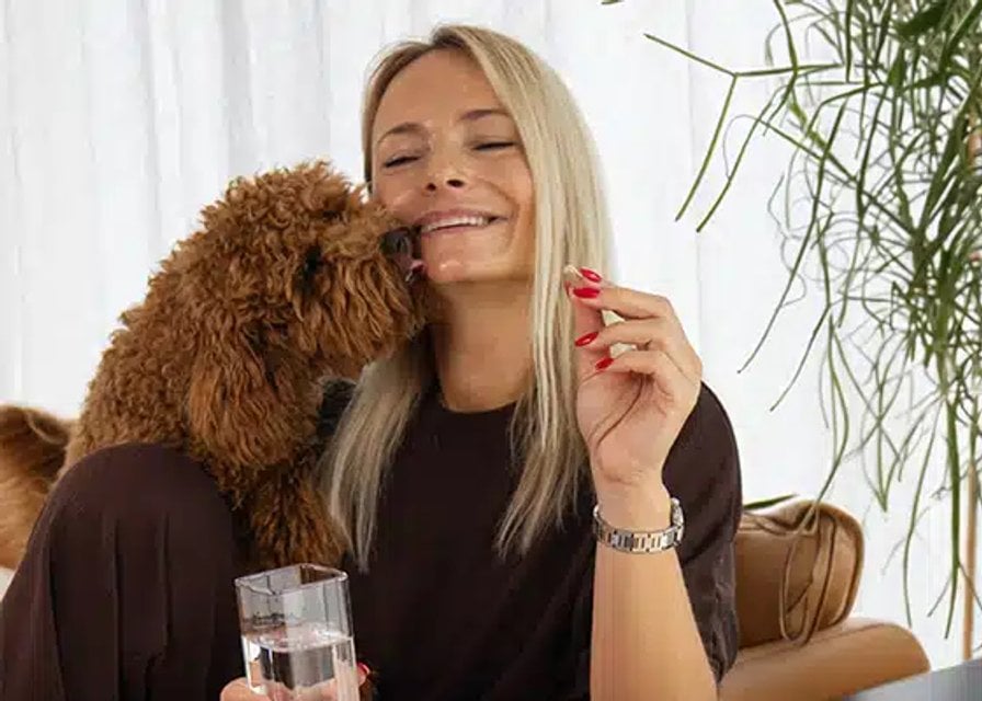 Femme assise avec un chien et un flacon KSM-66 Ashwagandha Nature’s Finest