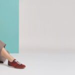Model seated in autumn clothing wearing burgundy Aetrex sneakers