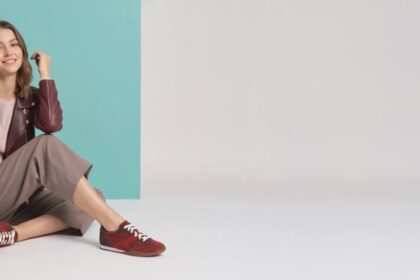 Model seated in autumn clothing wearing burgundy Aetrex sneakers