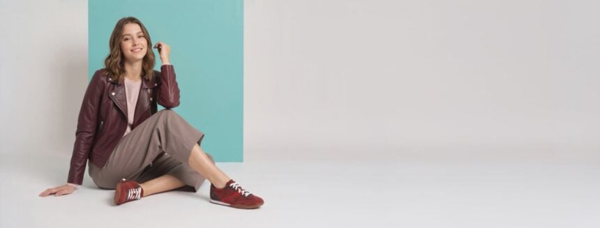 Model seated in autumn clothing wearing burgundy Aetrex sneakers