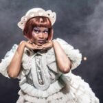 Cabaret performer posing in a white costume on stage