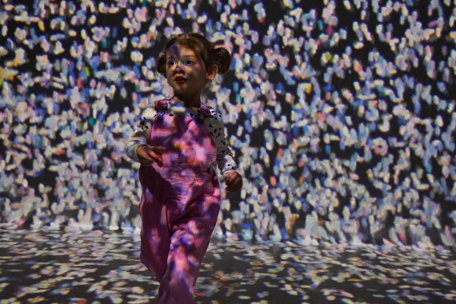 A child exploring a projected artwork inside Frameless