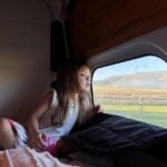 Child looking out from inside a camper at a Harvest Hosts location