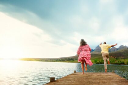 Two people running along a sunny pier