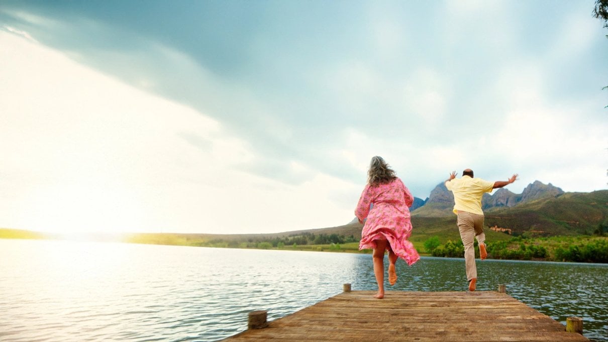 Two people running along a sunny pier