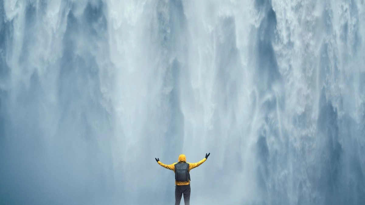 Person standing before a large waterfall