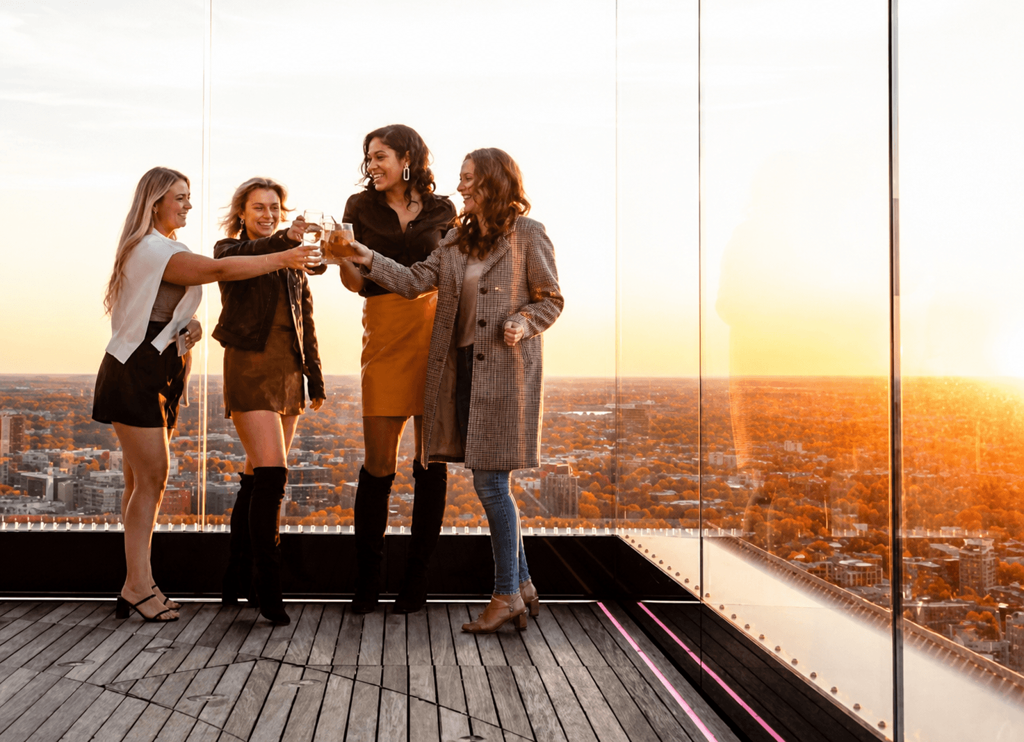 Four guests toasting drinks with Boston views