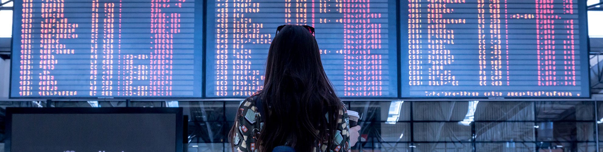Viaggiatrice davanti al tabellone delle partenze in aeroporto