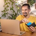 Hombre con portátil y cartera revisando información financiera