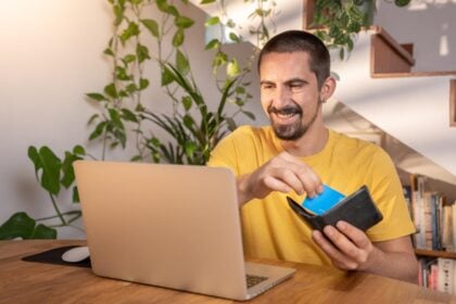 Hombre con portátil y cartera revisando información financiera