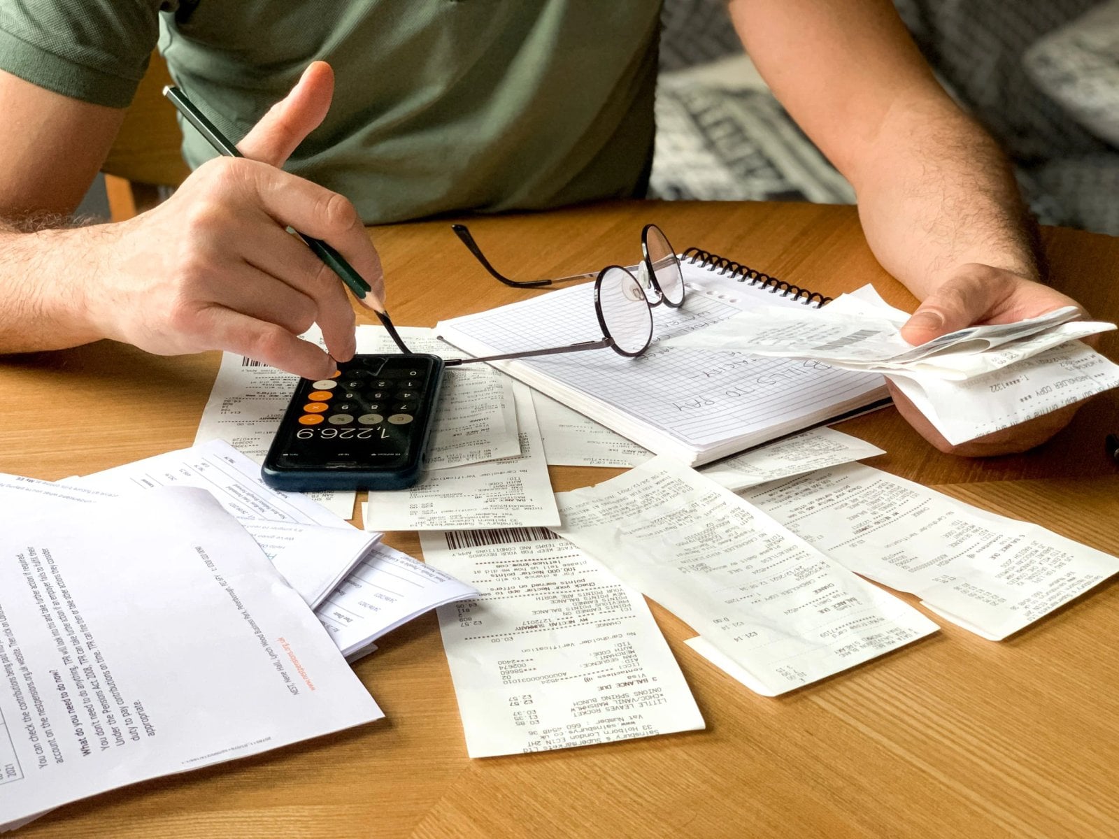 Persona organiza gastos del hogar con calculadora y recibos