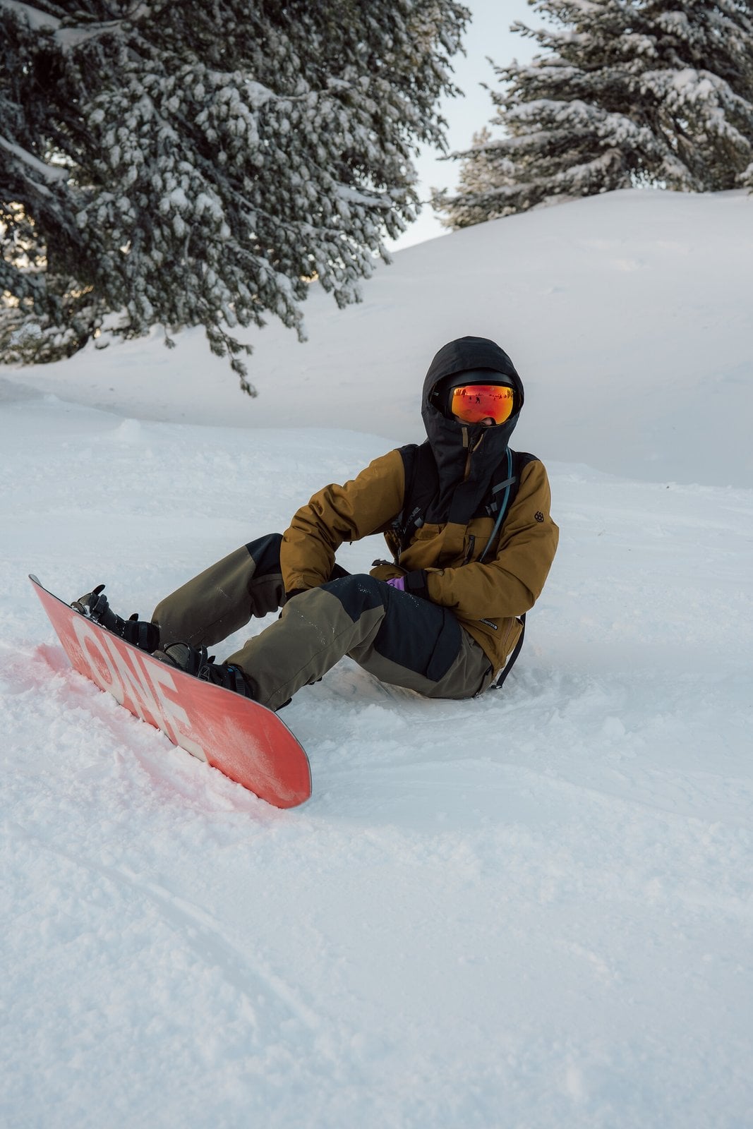 A snowboarder seated on a snowy slope
