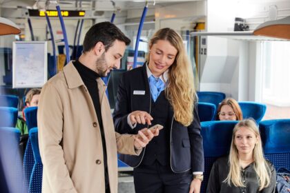 Schaffnerin prüft das digitale Ticket eines Fahrgasts im Regionalzug