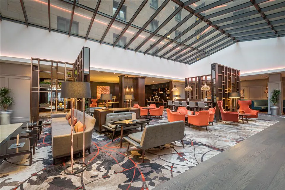 Bright hotel lobby with seating and a glass roof