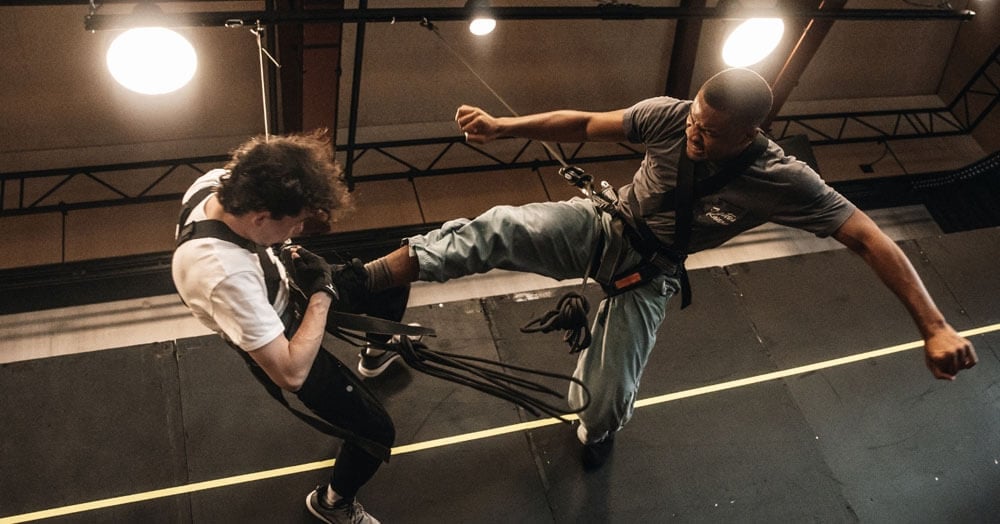 Two performers practising a fight sequence on a rehearsal stage