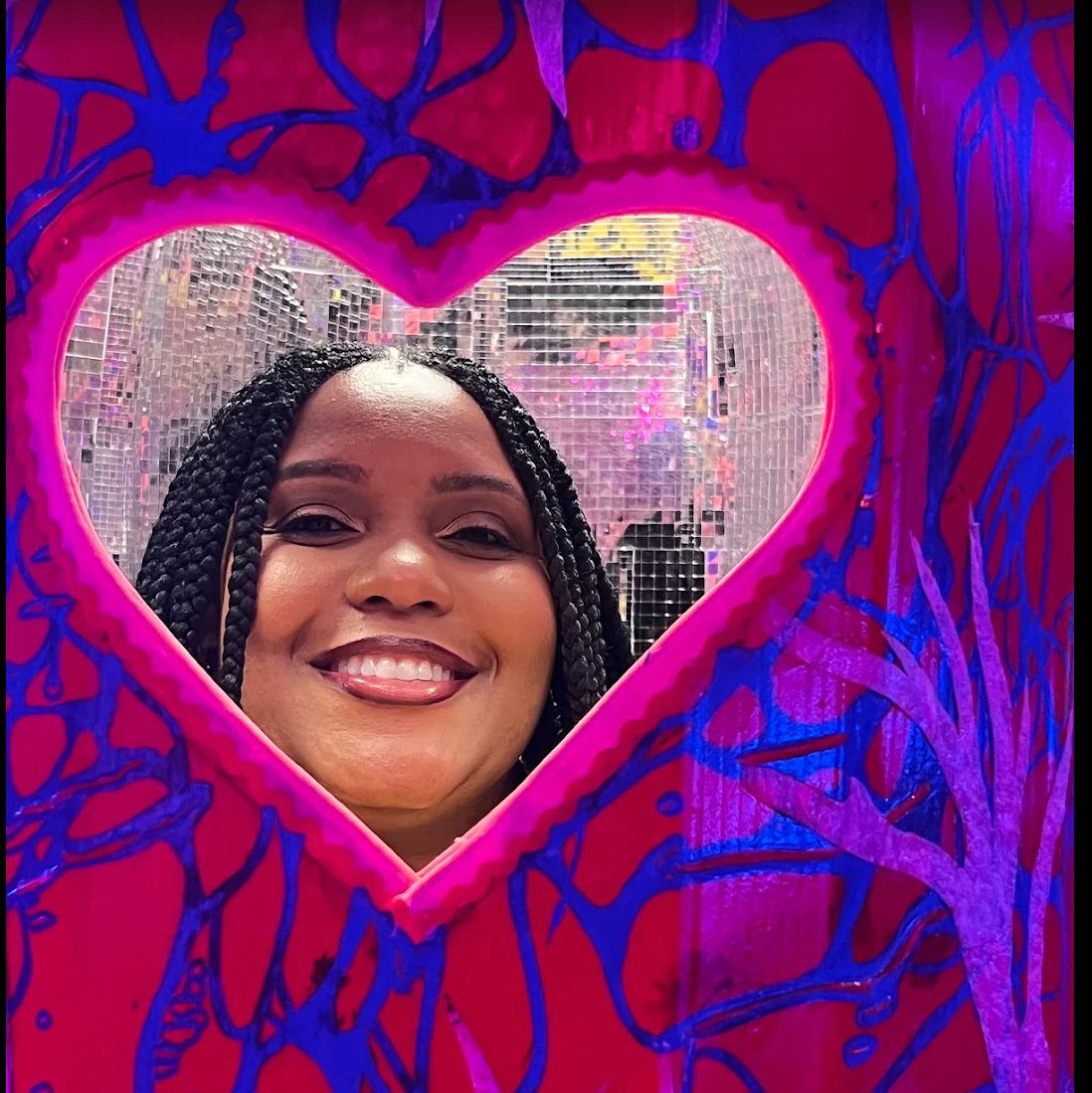 Visitor framed by a heart-shaped mirror with a disco ball backdrop at JAMNOLA
