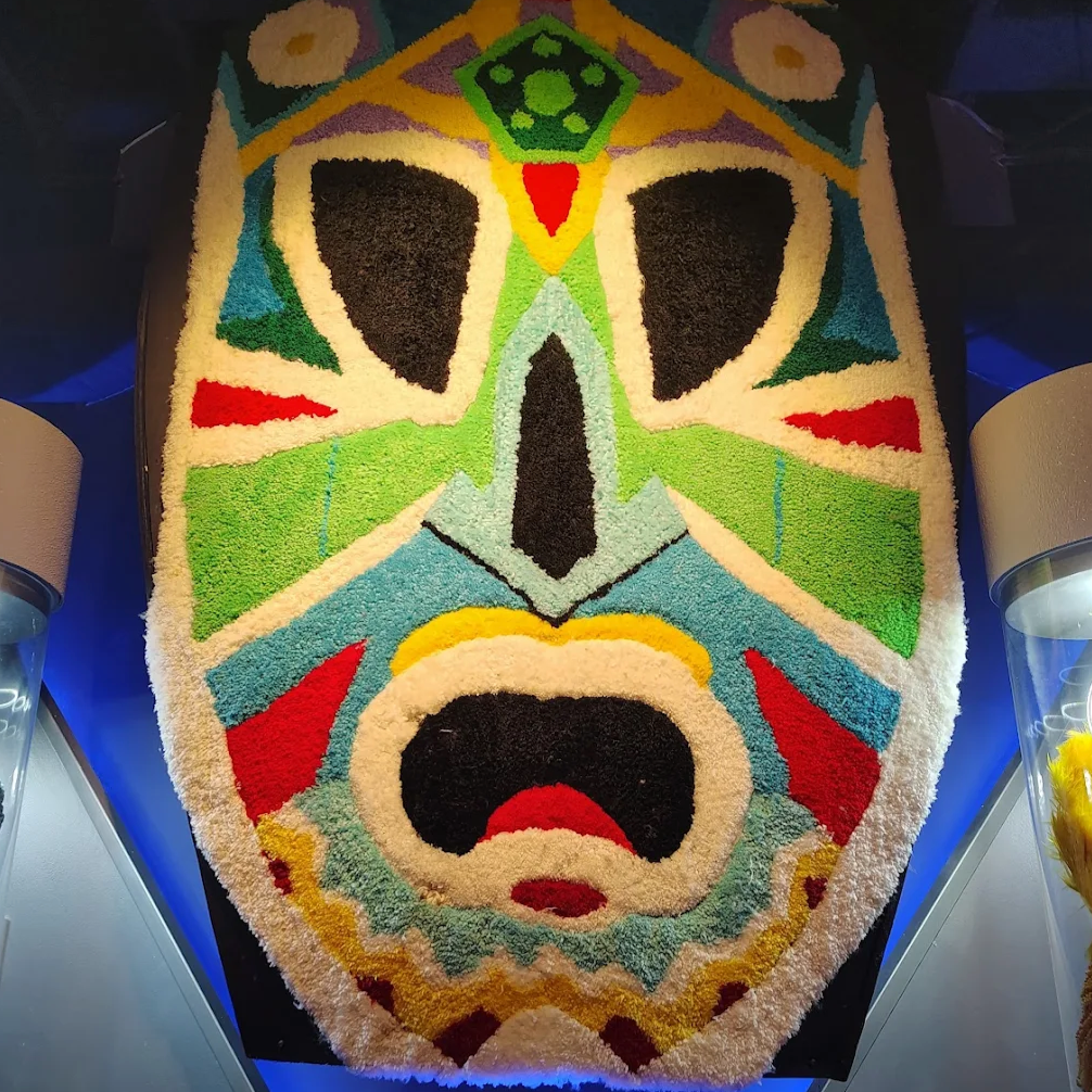 Colourful mask-shaped wall art on a blue background at JAMNOLA