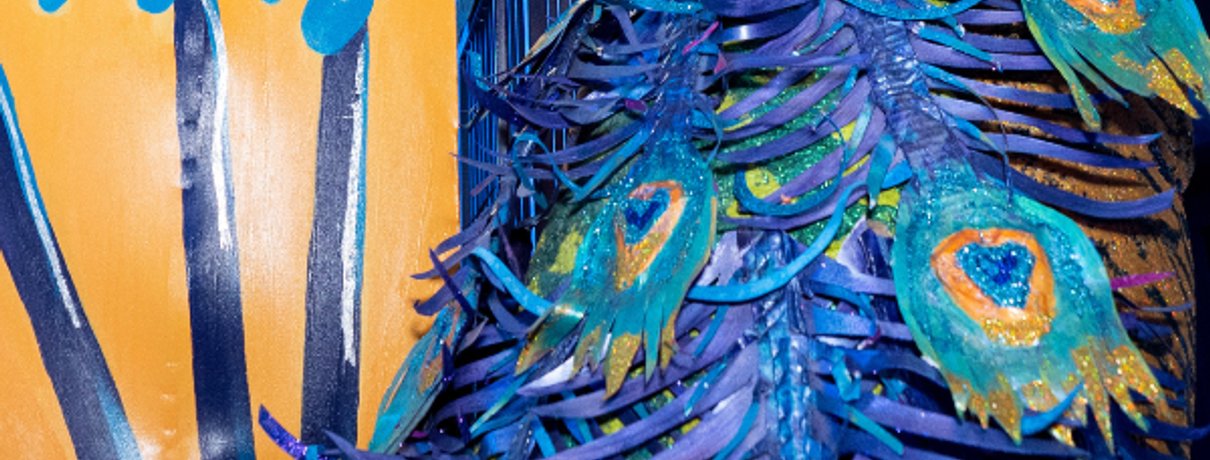 Visitor posing beside the giant decorative peacock sculpture at JAMNOLA New Orleans