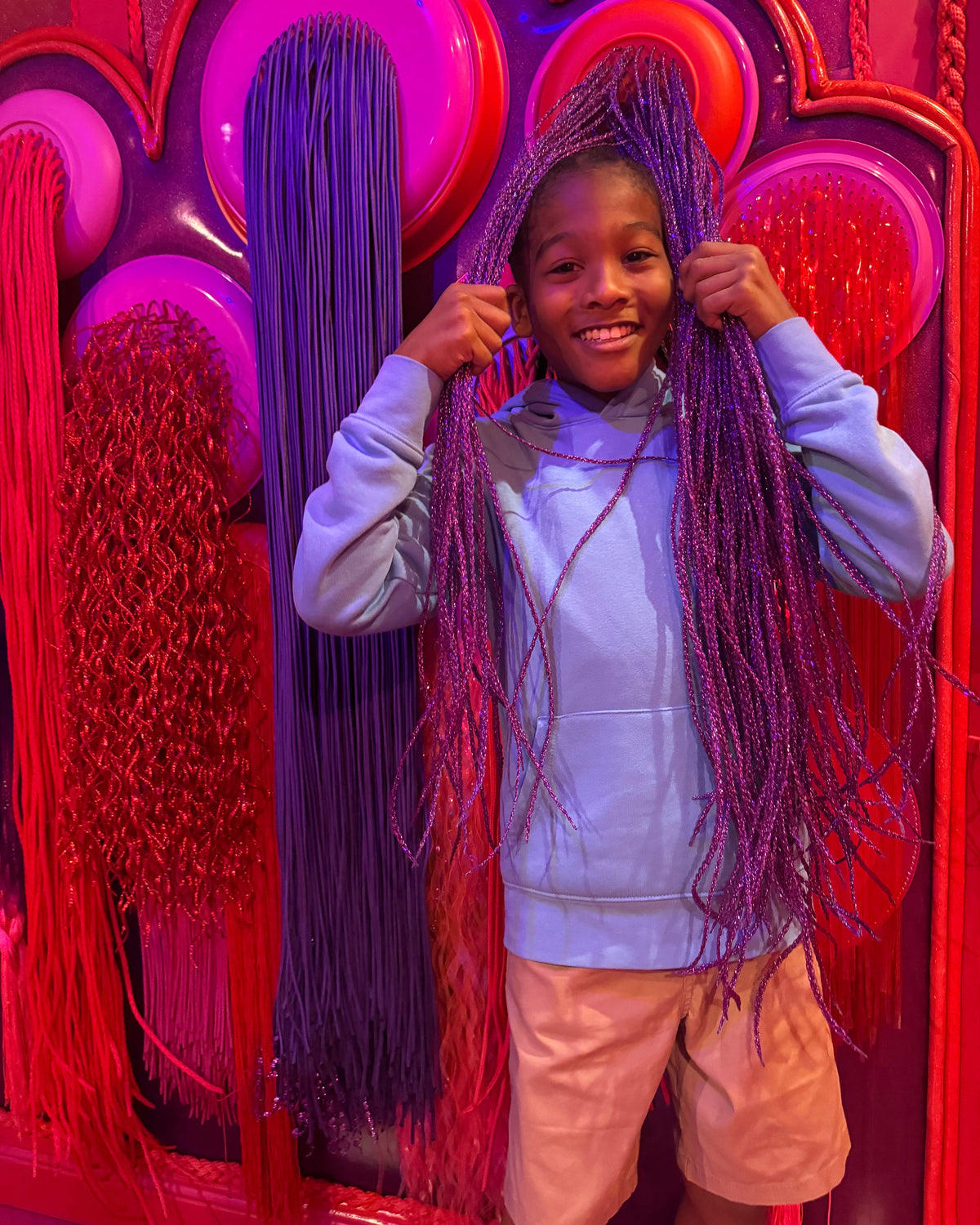 Visitor with braided hair posing in front of a vivid Rougerie mural at JAMNOLA