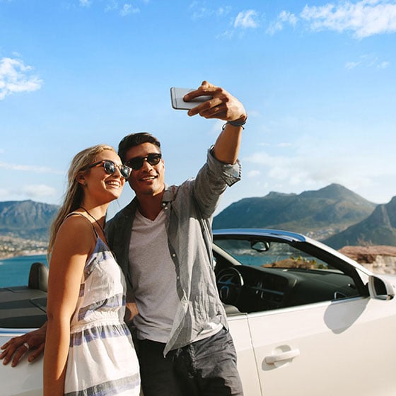 Paar macht ein Selfie neben einem Auto