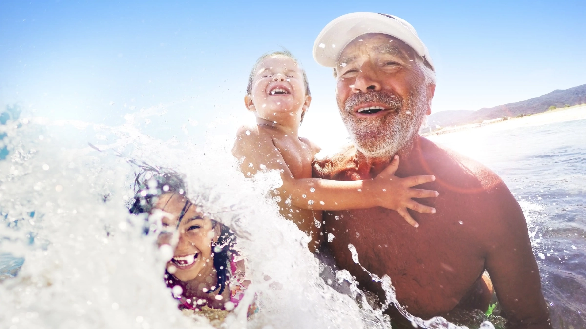 Grandfather swimming in the sea with children