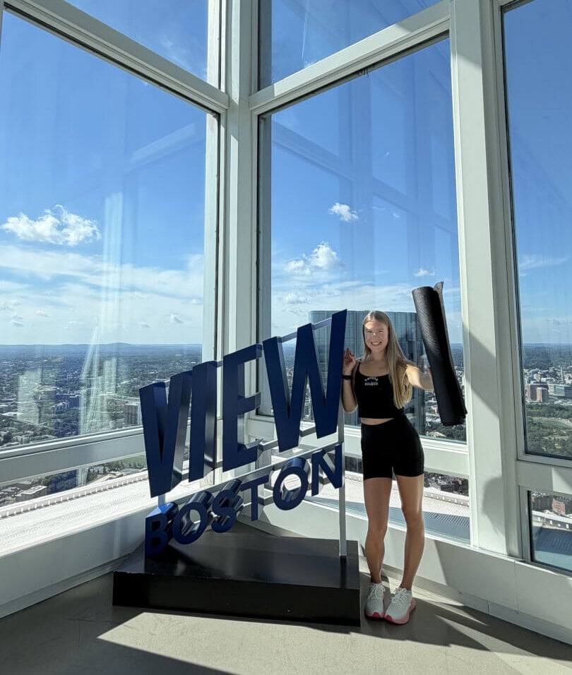 Woman standing beside a View Boston sign