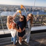 Visitors raising drinks above the Boston skyline at View Boston