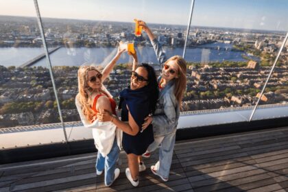 Visitors raising drinks above the Boston skyline at View Boston
