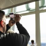 A man photographing the view through a View Boston window
