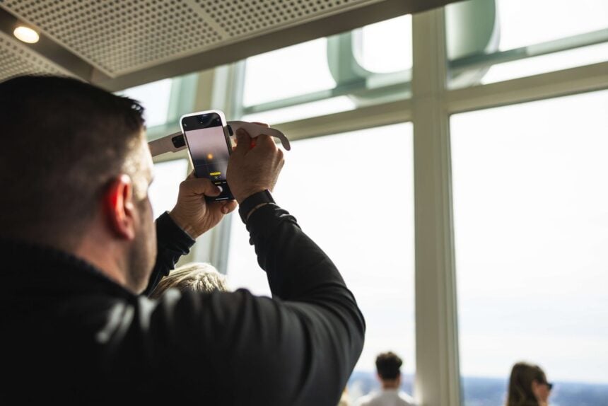 A man photographing the view through a View Boston window