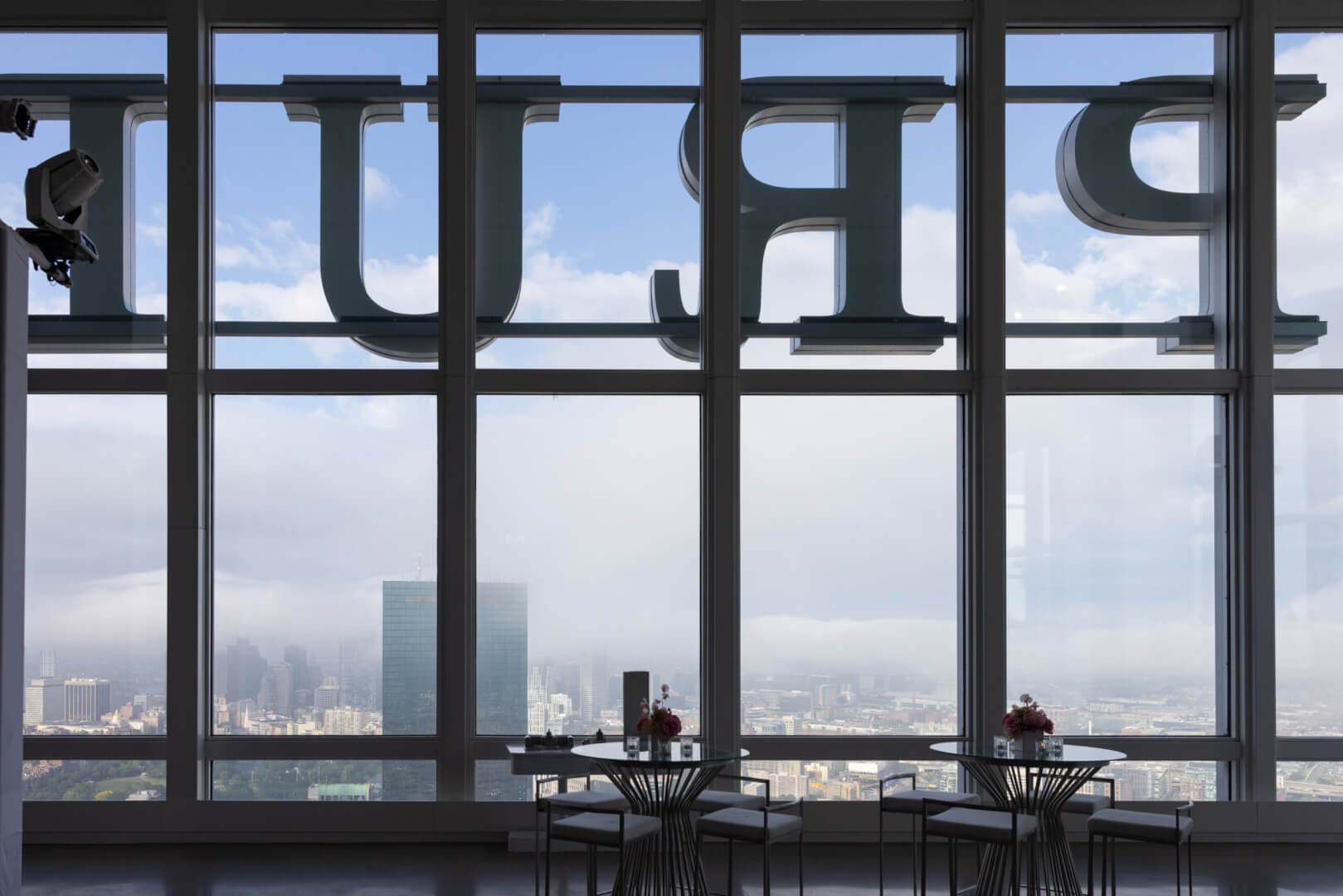 Empty tables beside skyline windows at View Boston